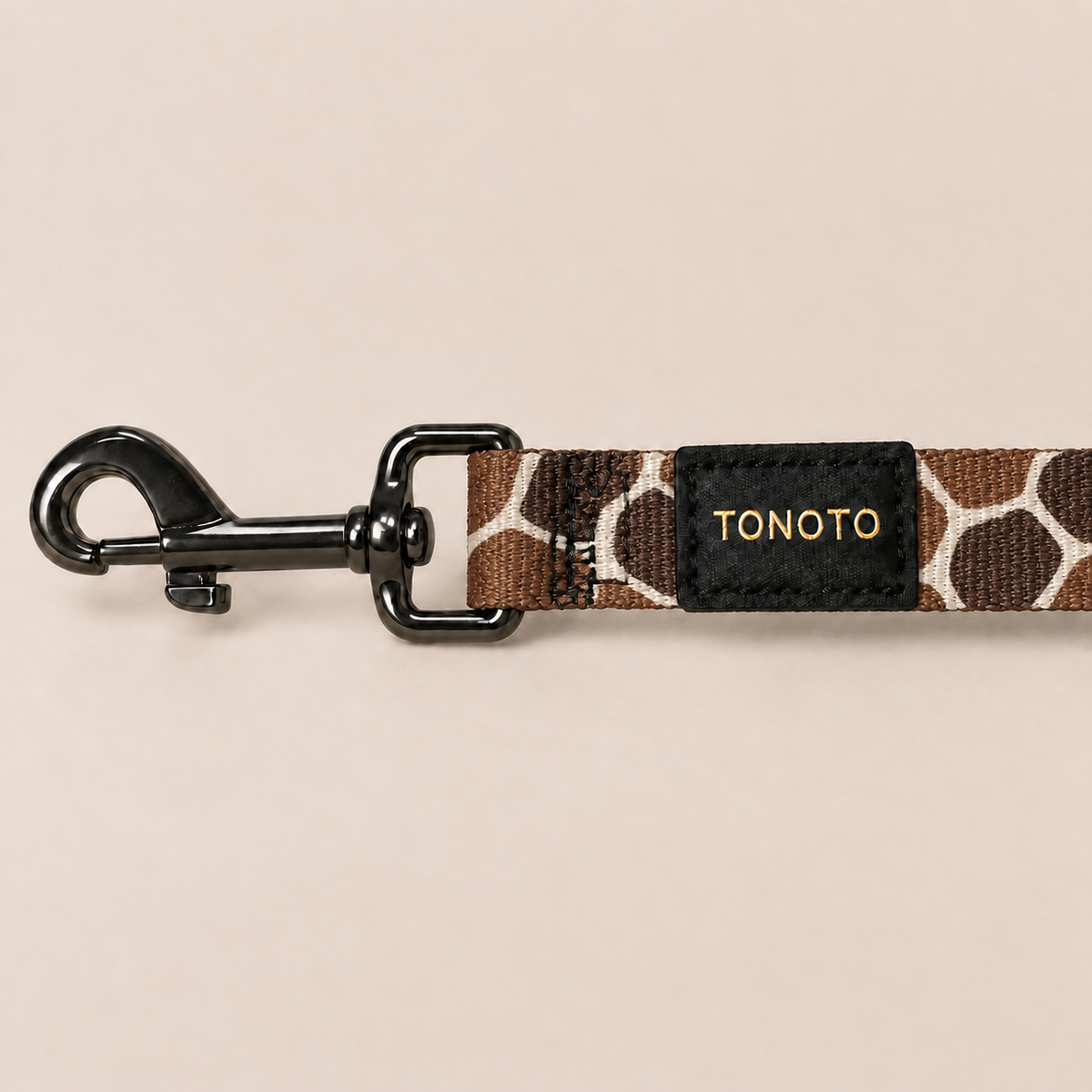 Close-up of giraffe pattern dog lead snap hook and TONOTO label